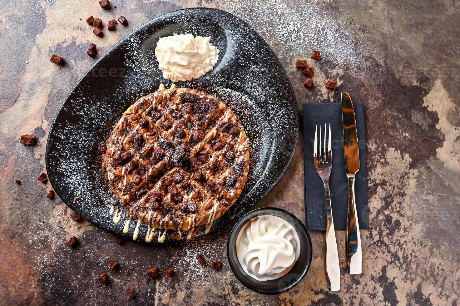 Oreos and Brownie Waffle with chocolate, whipped cream, knife and fork served in dish isolated on dark background top view cafe dessert food photo