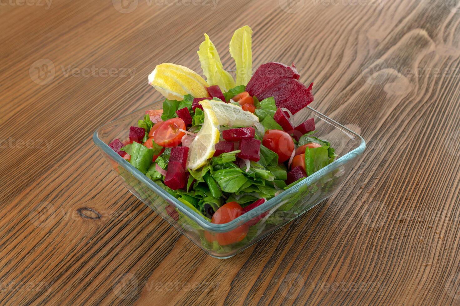 Arugula salad with spinach, cucumber, cherry tomato, onion and lemon served in dish isolated on wooden table side view of arabic food photo