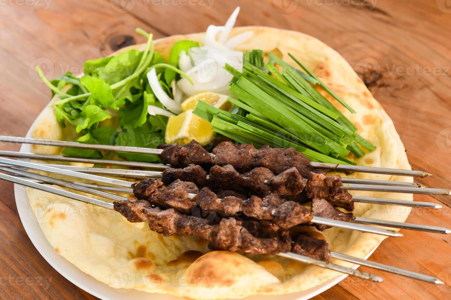 Swek of Tikka kabab with bahraini bread tandoori nan, lime and salad served in dish isolated on wooden table top view middle eastern grills food photo
