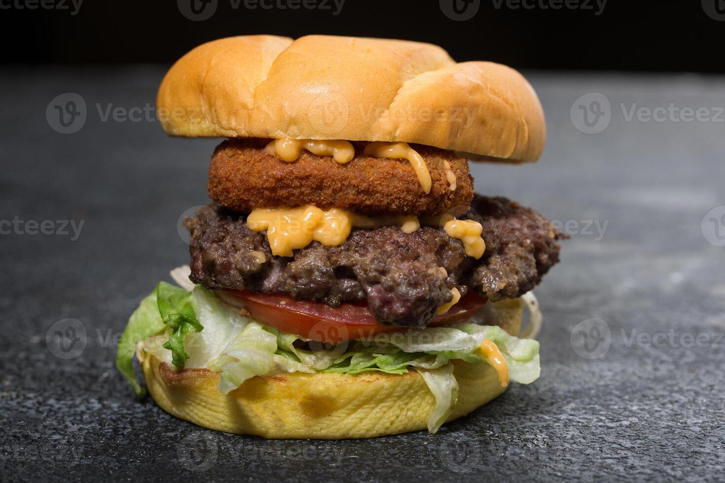 Jalapeno Beef Burger include melted cheese, cabbage, tomato and lettuce leaf isolated on dark grey background side view of fast food sandwich photo