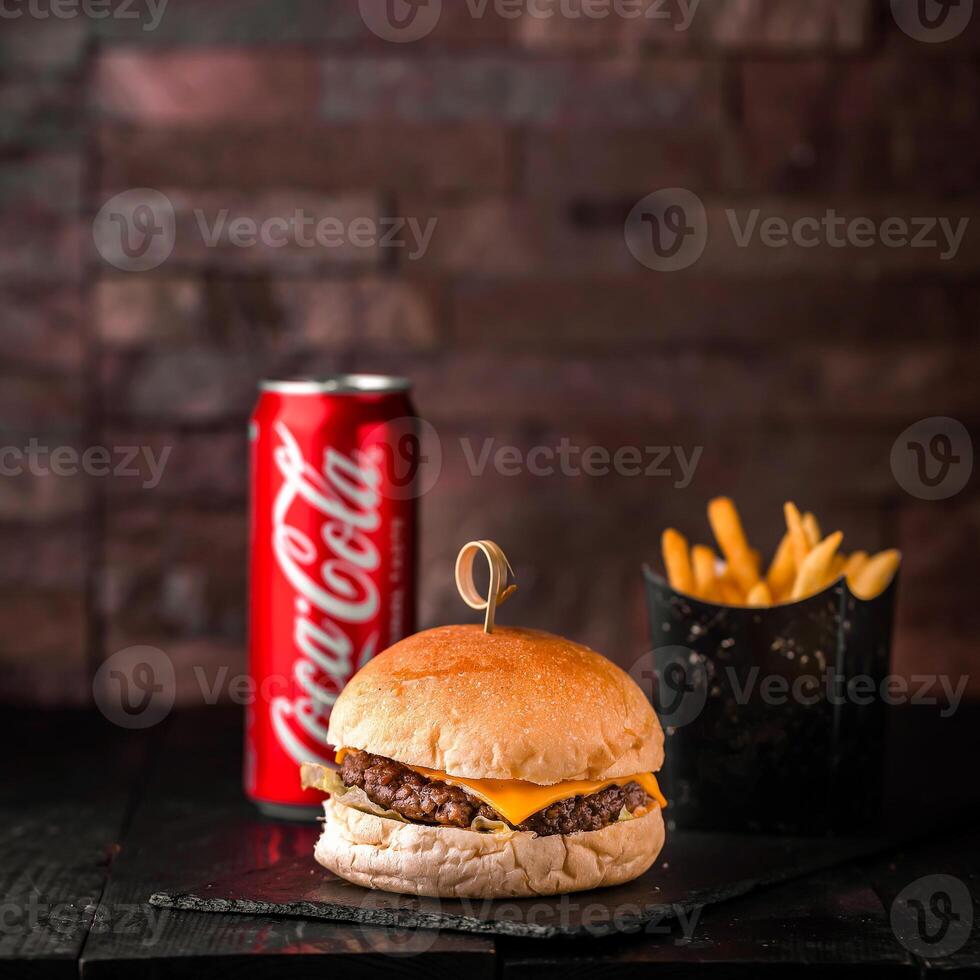 Beef Burger with fries bucket and coke can 250 ml served in dish isolated on wooden table side view of arabic fastfood photo