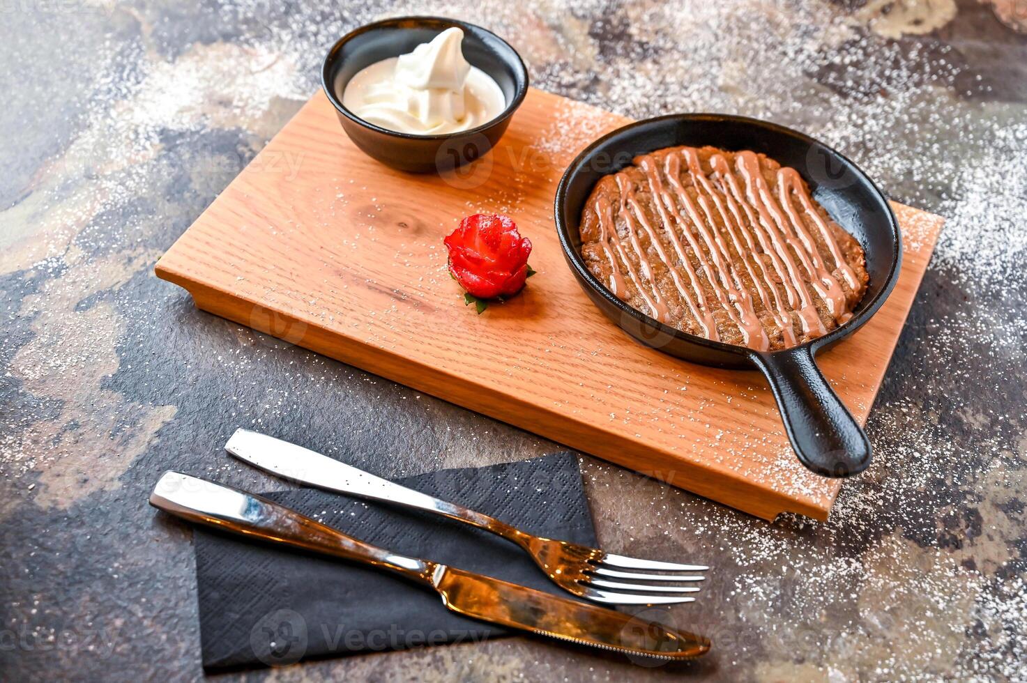 chocolate Chip Cookie dough with white chocolate, whipped cream, knife and fork served in dish isolated on dark background closeup top view of cafe baked dessert food photo