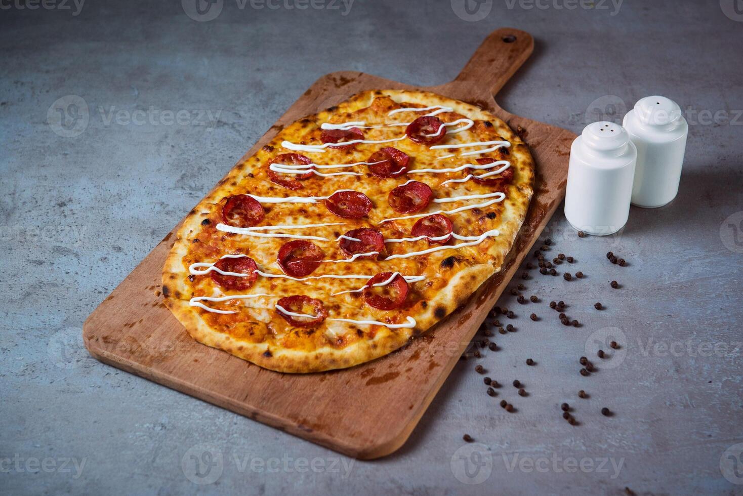 Pepperoni Pizza with black pepper serving on wooden cutting board isolated on grey background top view of fastfood photo