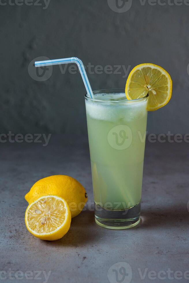 Healthy Lemon Juice limo pani fresh juice served in glass with lemon slice and straw side view on grey background photo