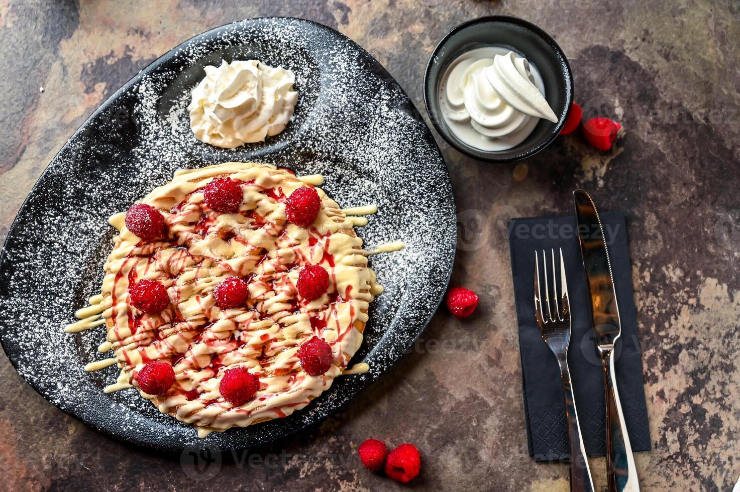 Raspberry Waffle with white chocolate, whipped cream, knife and fork served in dish isolated on dark background top view cafe dessert food photo