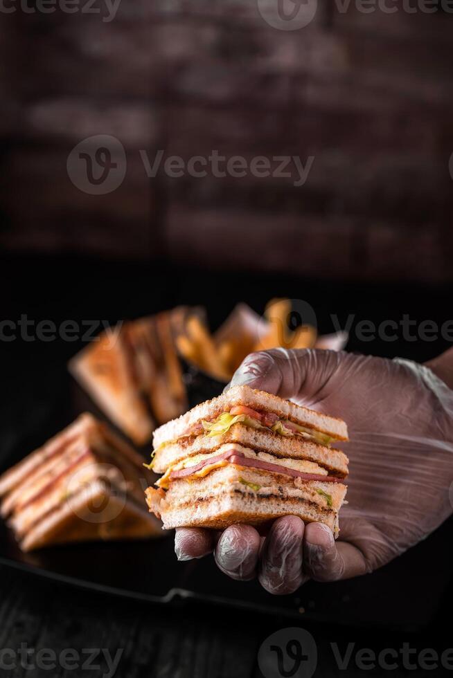 Club Sandwich in hand isolated on wooden table side view of arabic food photo
