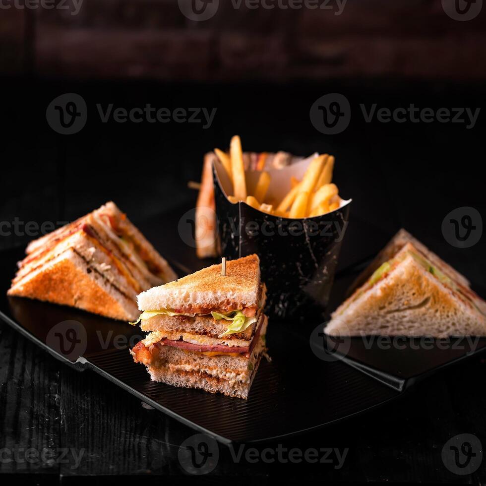 Club sandwiches with french fries bucket served in dish isolated on wooden table side view of arabic food photo
