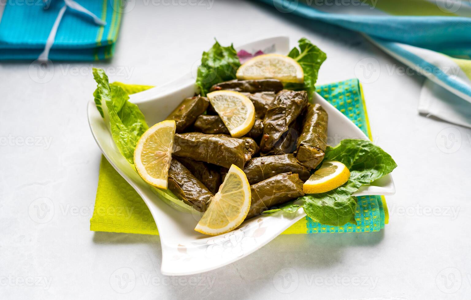 Vine leaves wrap filled with lemon slice served in dish isolated on table top view of arabic food photo