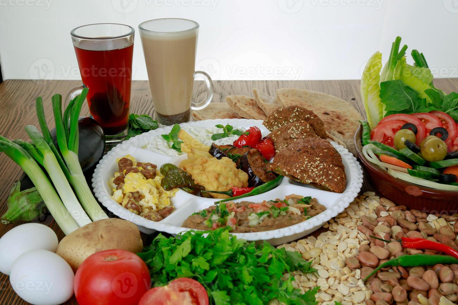 Arabic Dynamite breakfast platter with flafel, marinated fried eggplant, mashed potato, hummus, foul, beans, pita bread, salad and coffee drink isolated on table side view photo