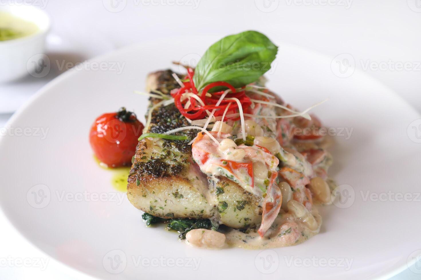 HERB CRUSTED HAMOUR FILLET with sauce closeup served in dish isolated on table top view of arabic food photo