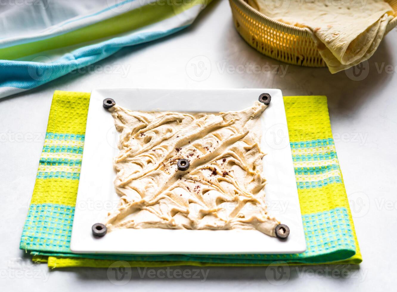 Tasty Hummus topping with black olive served in dish isolated on table top view of arabic food photo