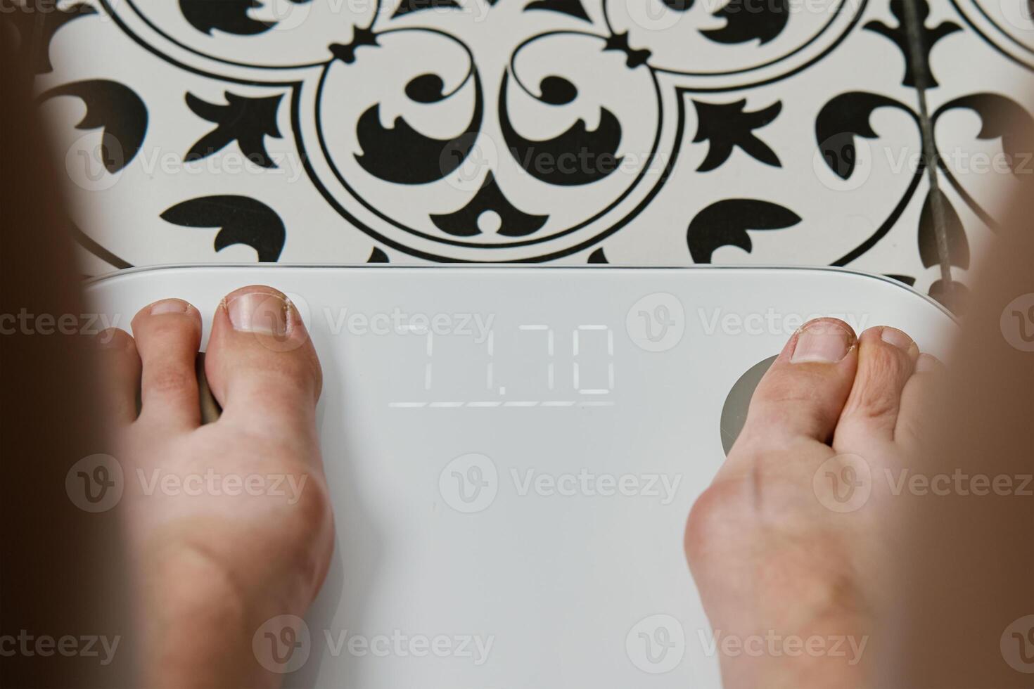 Woman checking her weight on weighing scales in bathroom photo