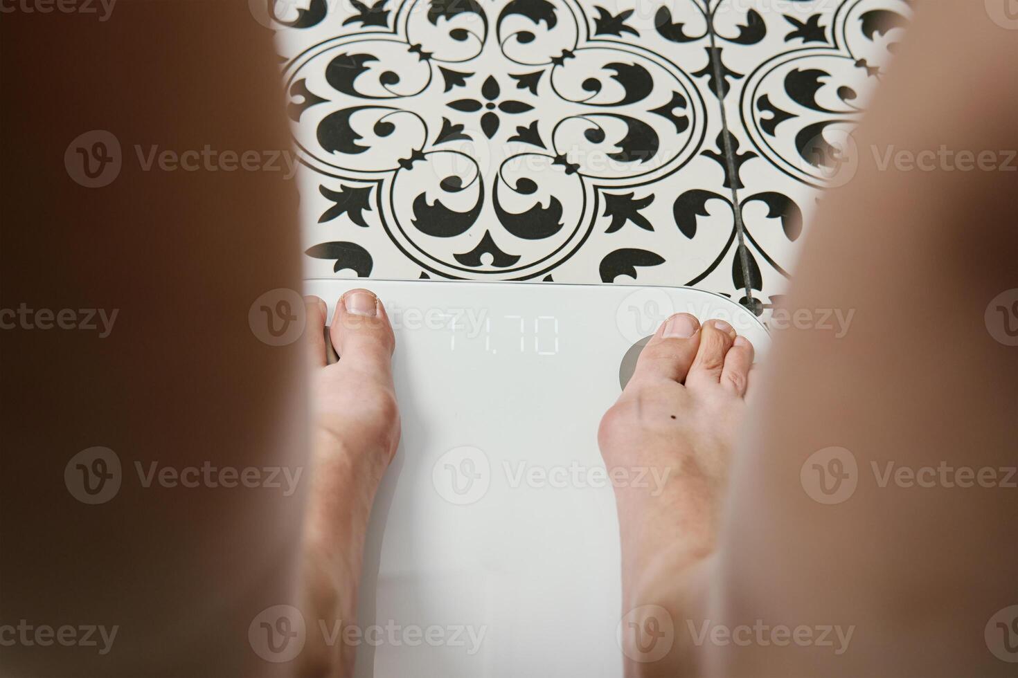 Woman checking her weight on weighing scales in bathroom photo