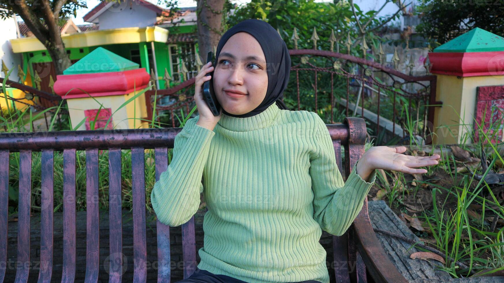 Happy asian muslim woman talking on mobile phone in park, free space photo