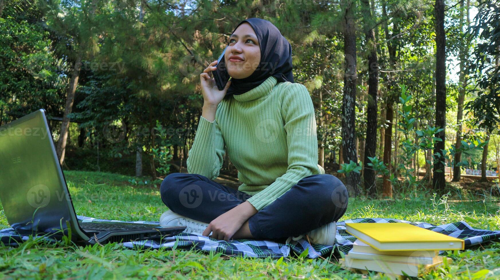 Happy muslim woman having video call on mobile phone at park, using headset, free space photo