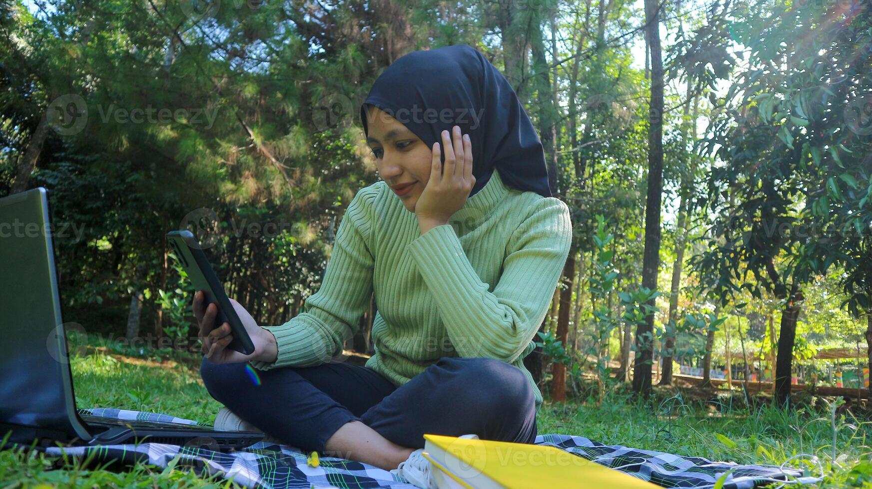 Happy muslim woman having video call on mobile phone at park, using headset, free space photo