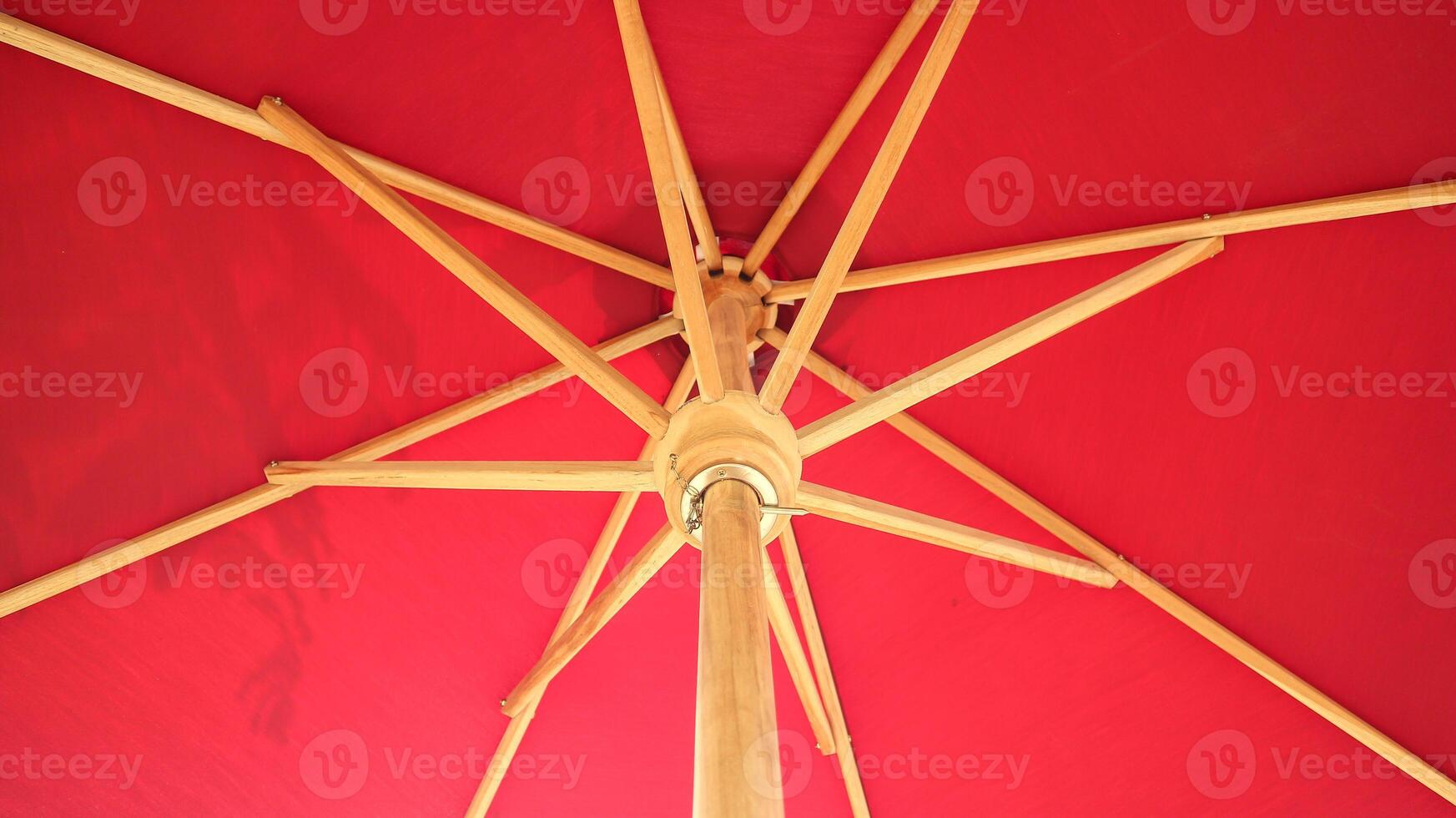 Crossing wooden umbrella structure create an abstract pattern on red background photo