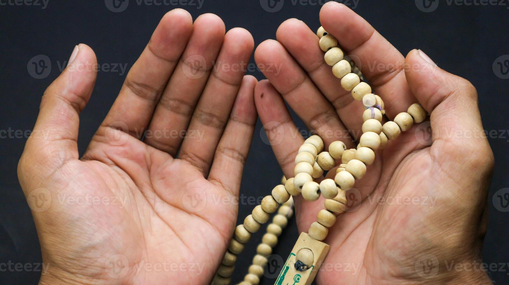 Overhead view of hands holding prayer beads with black background. photo