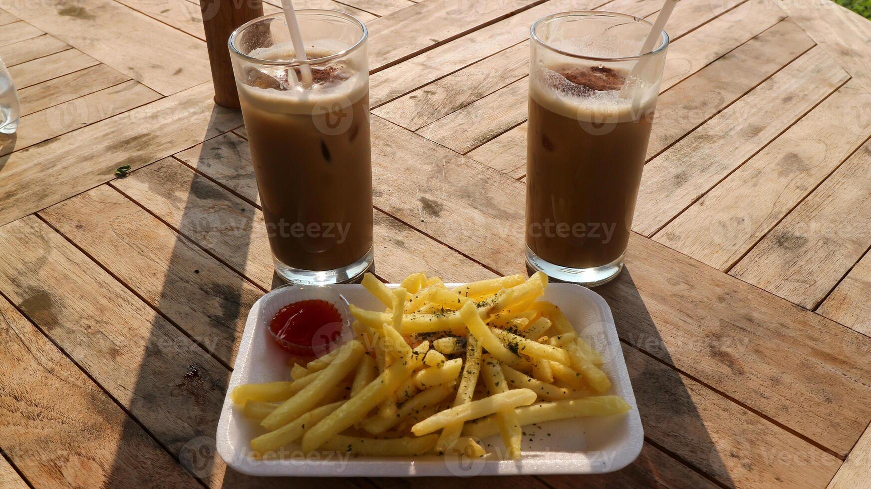 french fries, sauce, milk, chocolate on a wooden table with natural scenery as a background. photo