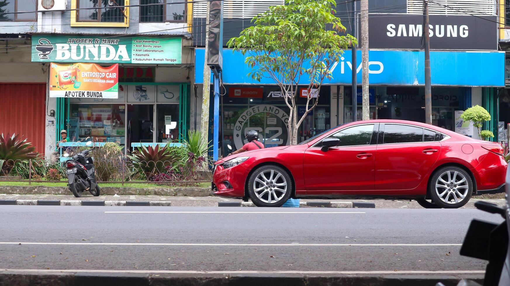 rojo coche mazda estacionado en el la carretera en contra el antecedentes de el soleado cielo. automotor fotografía. foto