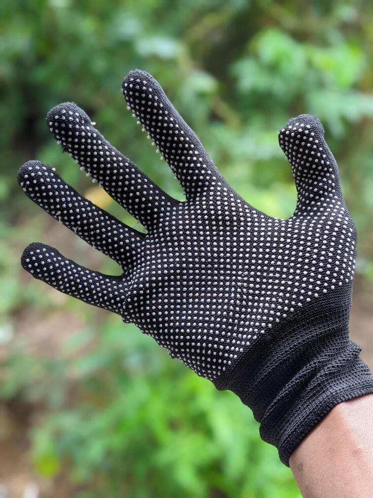 A man is wearing black body gloves with blurred on background at the garden photo