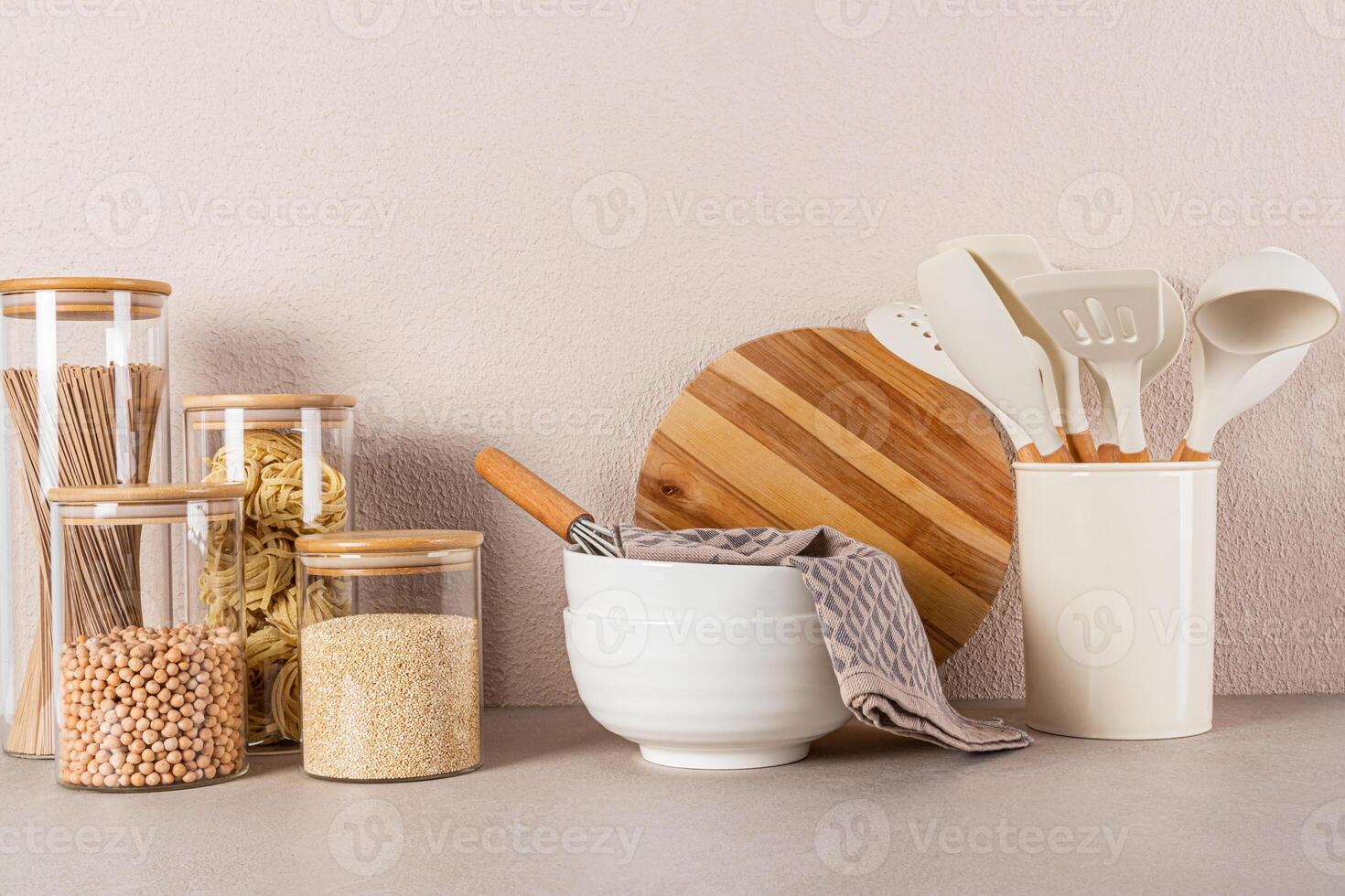 Two large ceramic bowls, a set of bulk food jars, a set of cooking tools on a stone countertop. Beautiful kitchen background. Front view. Eco cuisine photo