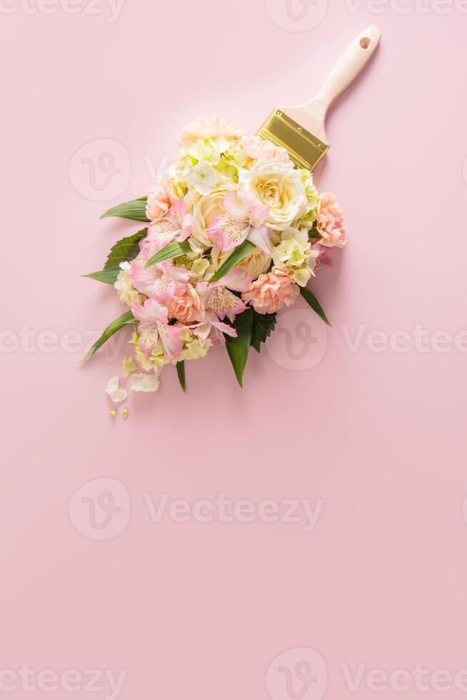 Brush paints with flowers, spring concept on pastel pink background. Minimal nature flat lay. A copy space. Vertical view. photo