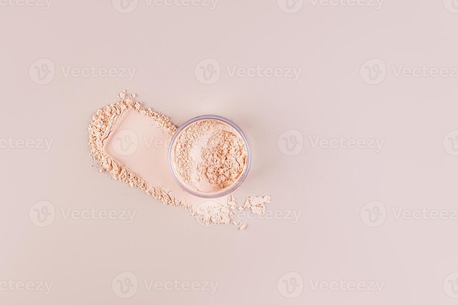 An open jar with loose powder in a natural tone and a swatch of powder on a pastel background. Top view. Decorative cosmetics concept. photo