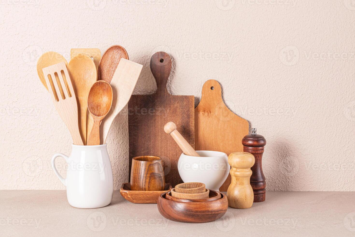 Set of various wooden cookware and utensils on a stone countertop by beige textured hay. Eco-friendly cuisine. Front view. photo