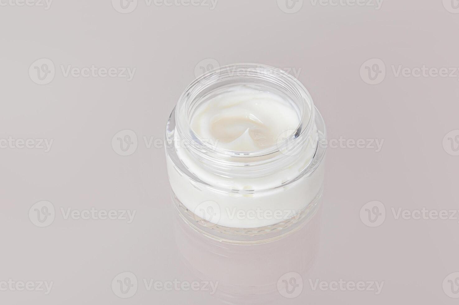 Delicate texture of white cosmetic cream for face and body skin care in jar on a glass background with reflection. layout. photo