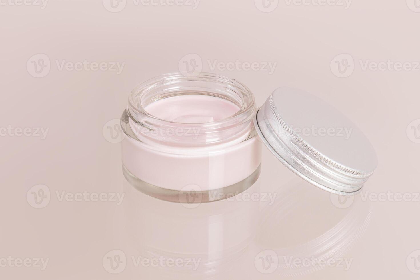 open cosmetic glass jar with cream for everyday self-care on a beige background and a glass surface. Front view. a copy space. photo