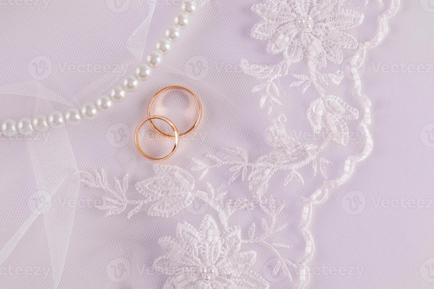 Chic wedding background for greeting card, invitation, cover design. delicate white embroidery flowers, two gold wedding rings, pearl beads. photo