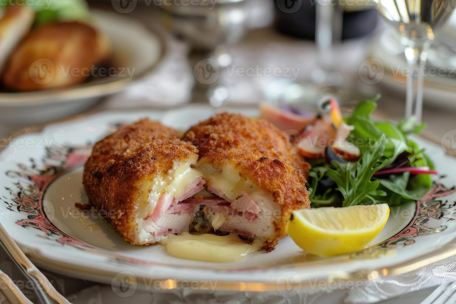 Breaded cutlet stuffed with ham and cheese, sliced in half to reveal the melty interior, on a fine porcelain plate. photo