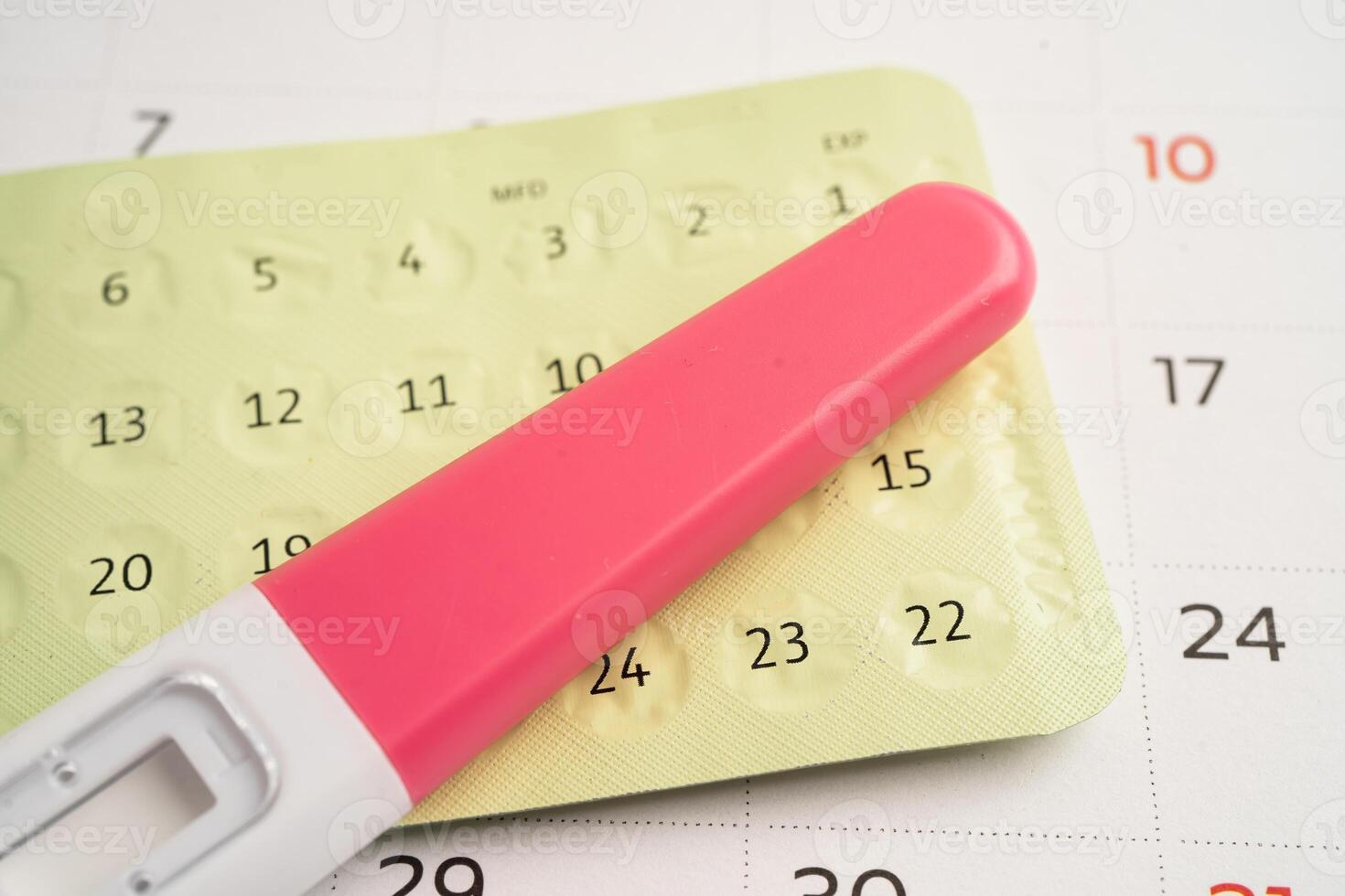 Pregnancy test and birth control pills on calendar, contraception health and medicine. photo