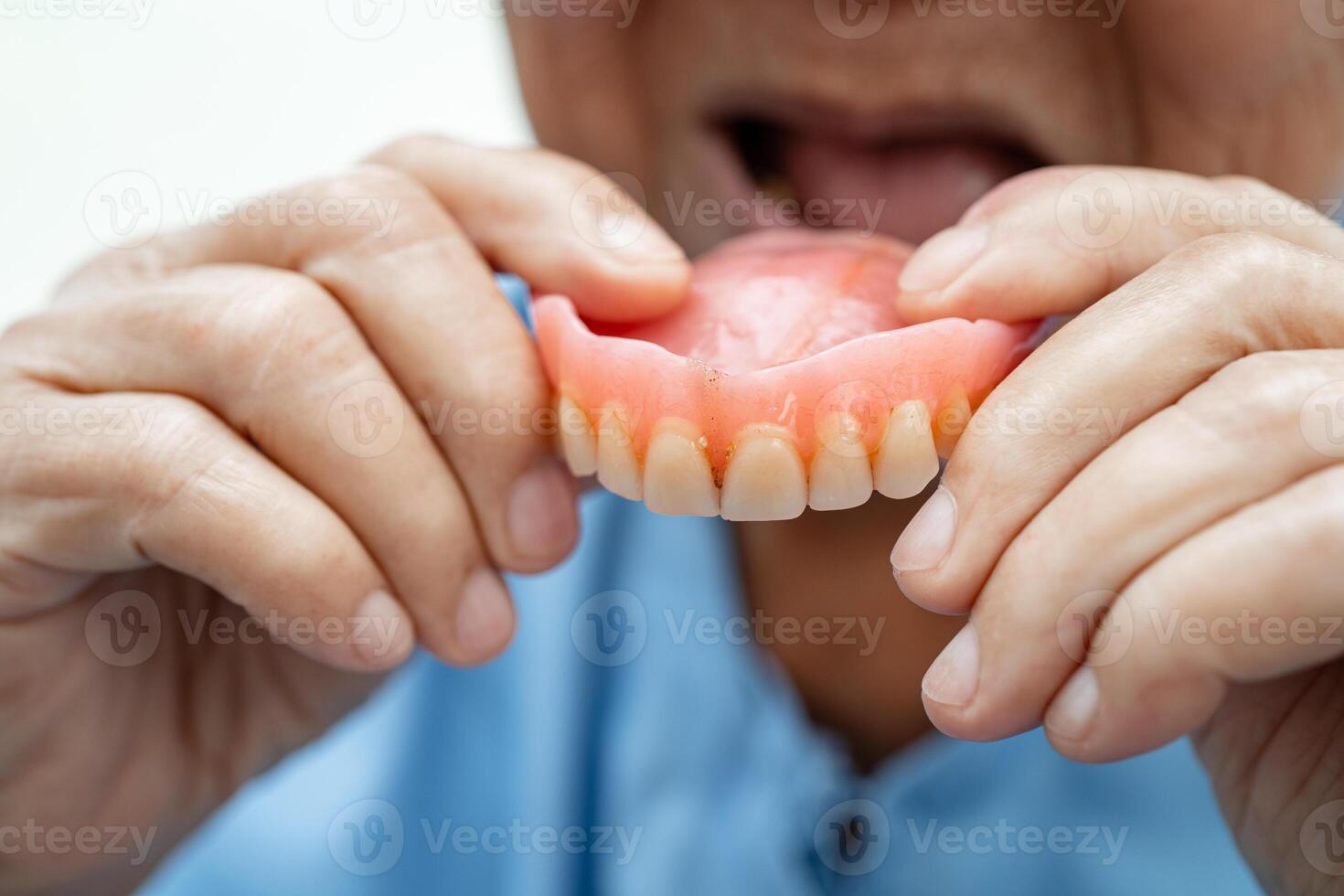 Asian elderly woman patient holding to use denture, healthy strong medical concept. photo