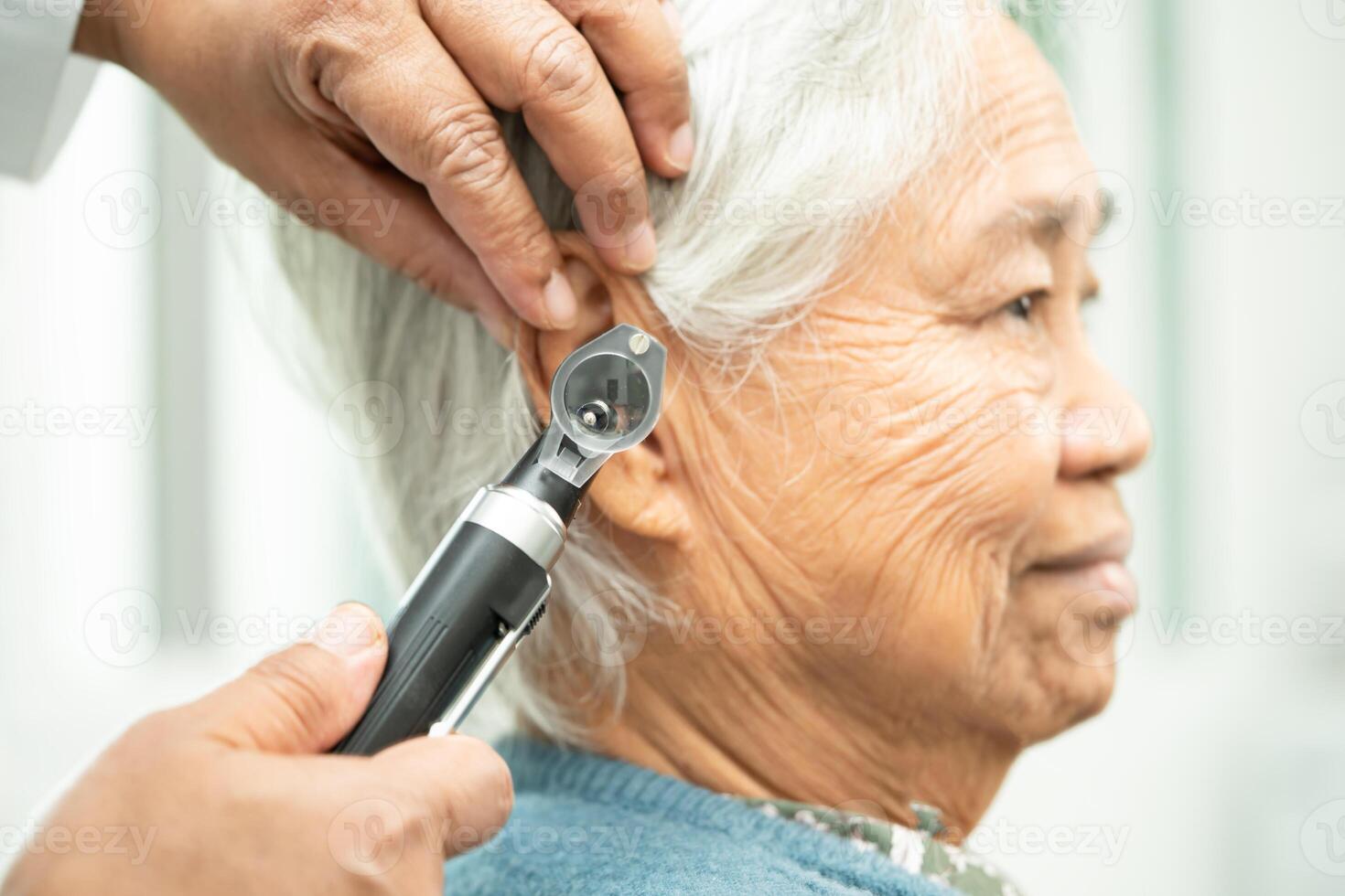 Audiologist or ENT doctor use otoscope checking ear of asian senior woman patient treating hearing loss problem. photo