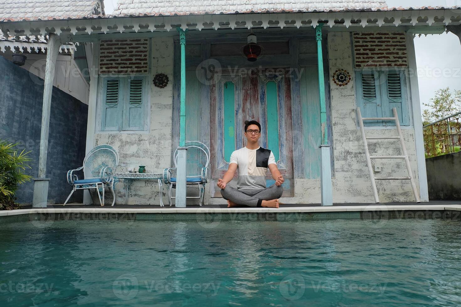 junto a la piscina serenidad, asiático modelo en loto yoga pose, bali villa relajación foto