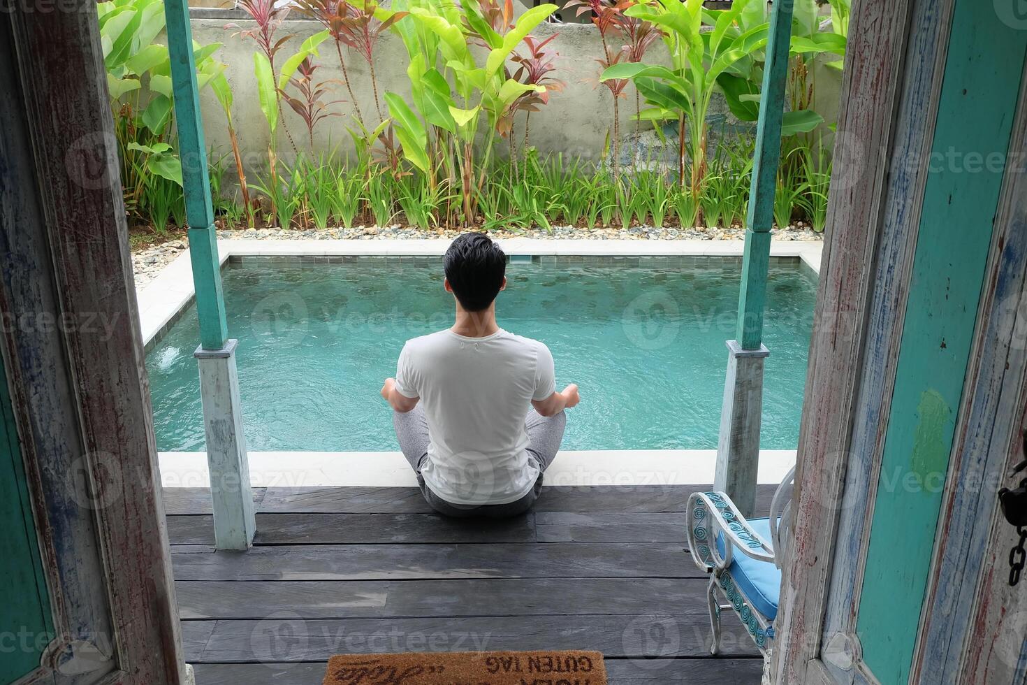 junto a la piscina serenidad, asiático modelo en loto yoga pose, bali villa relajación foto