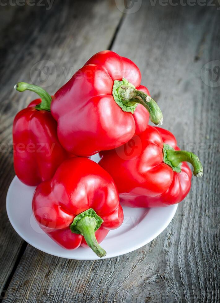 Red bell peppers on the wooden background photo