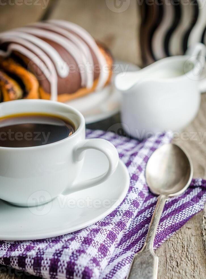 Cup of coffee and poppy bun glazed with ganache photo