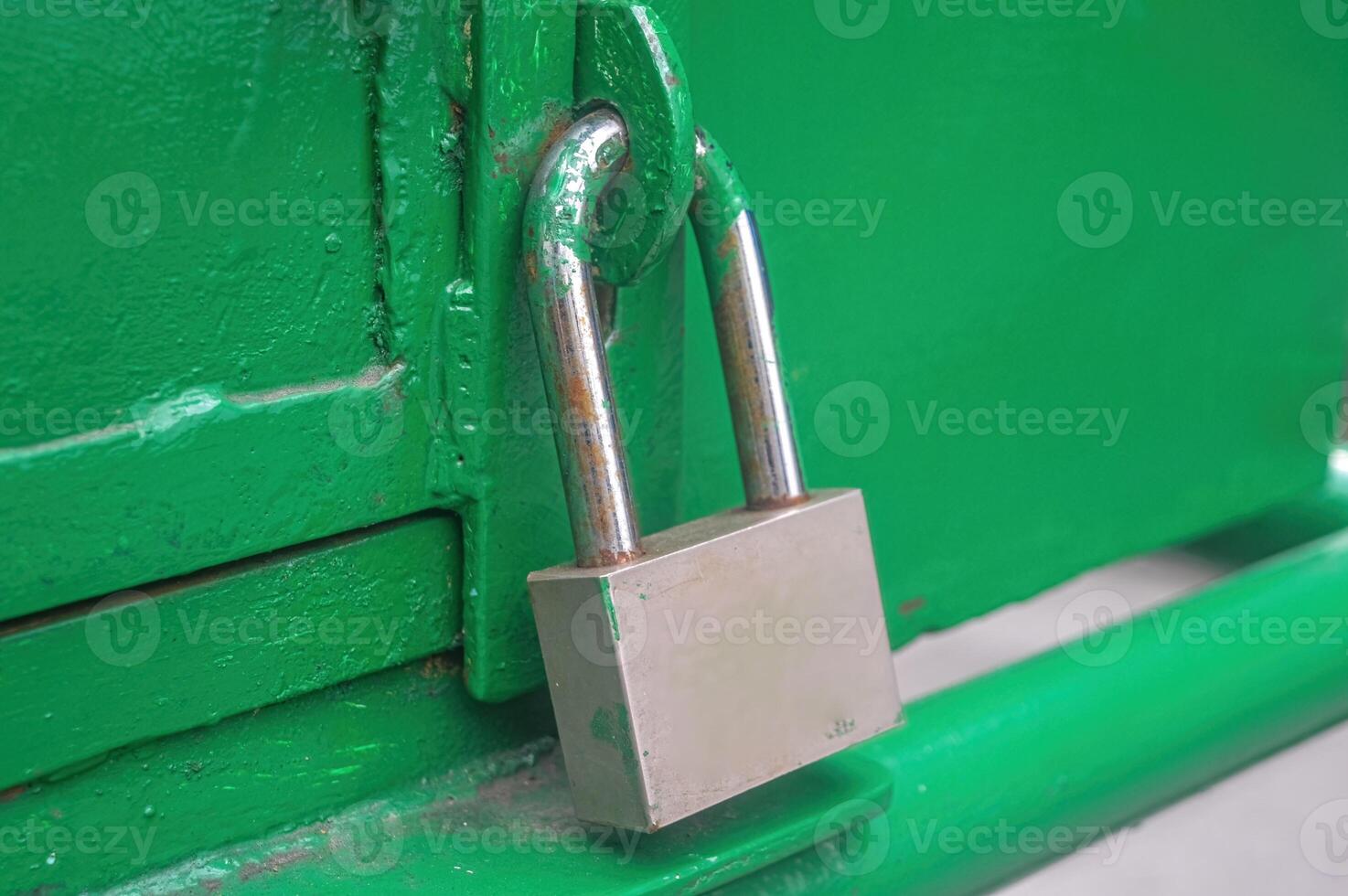 an iron padlock that locks the green iron door photo