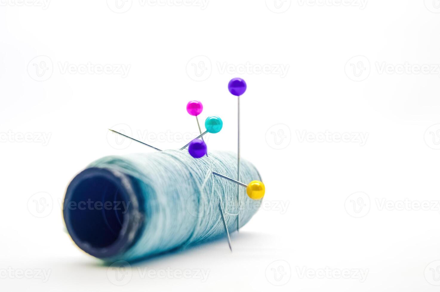a roll of sewing thread pierced by a pin isolated on white background with copy space photo