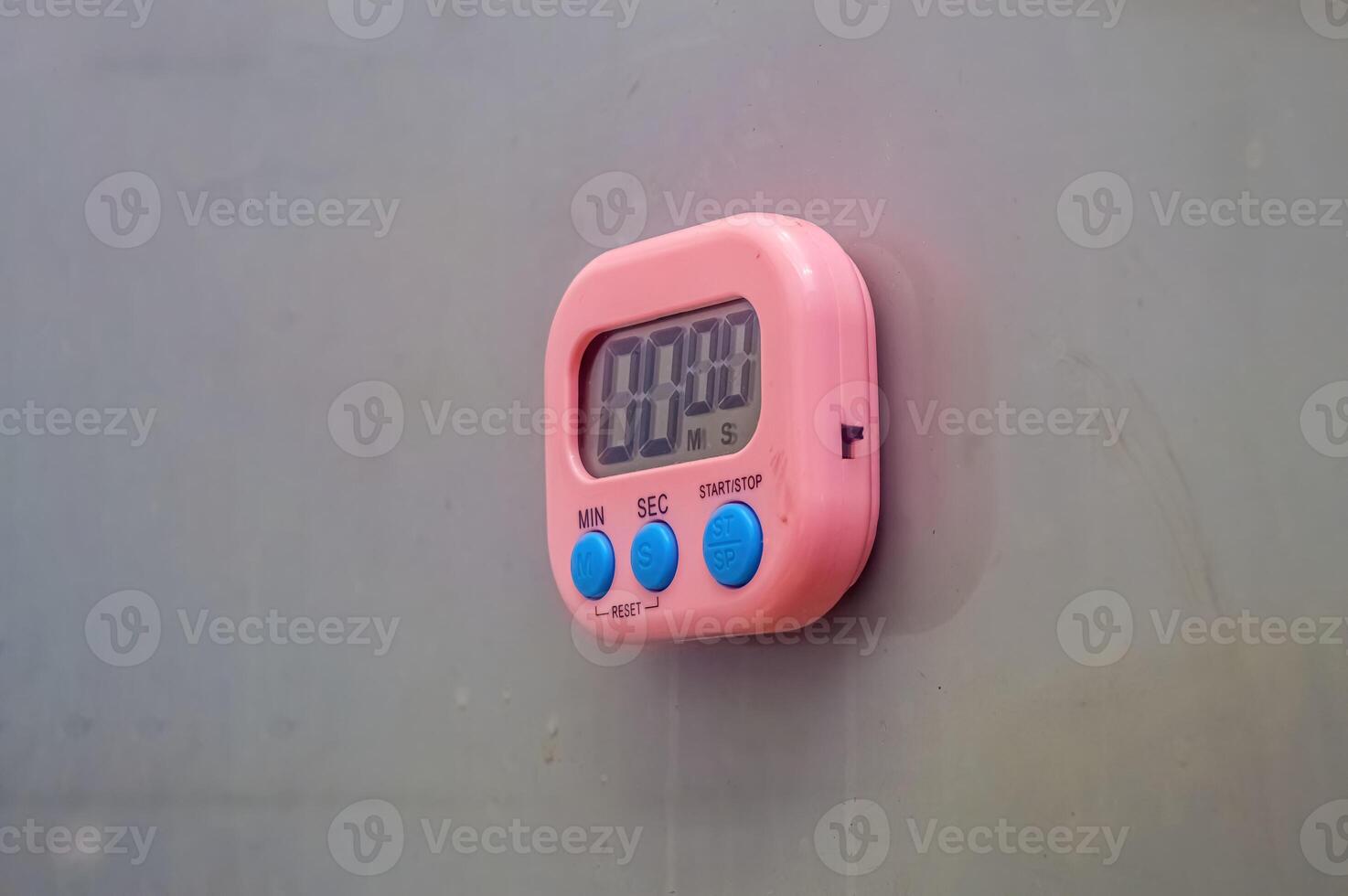 a pink digital timer stuck to the gray wall photo