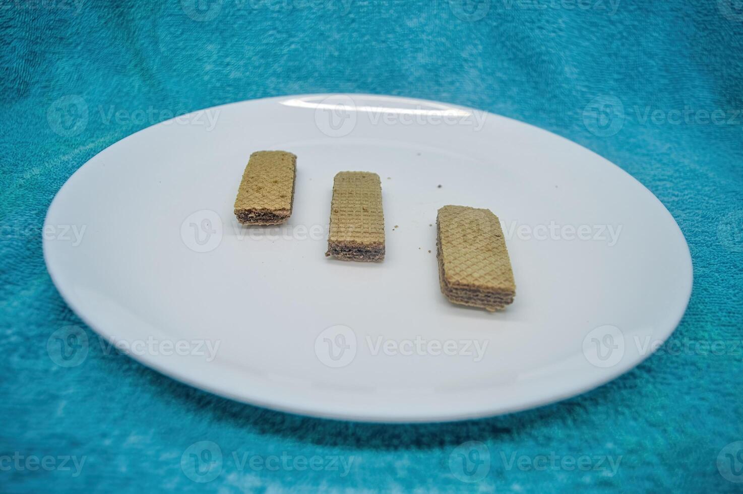 several wafers or wafers arranged on a plain white plate on a turquoise background photo