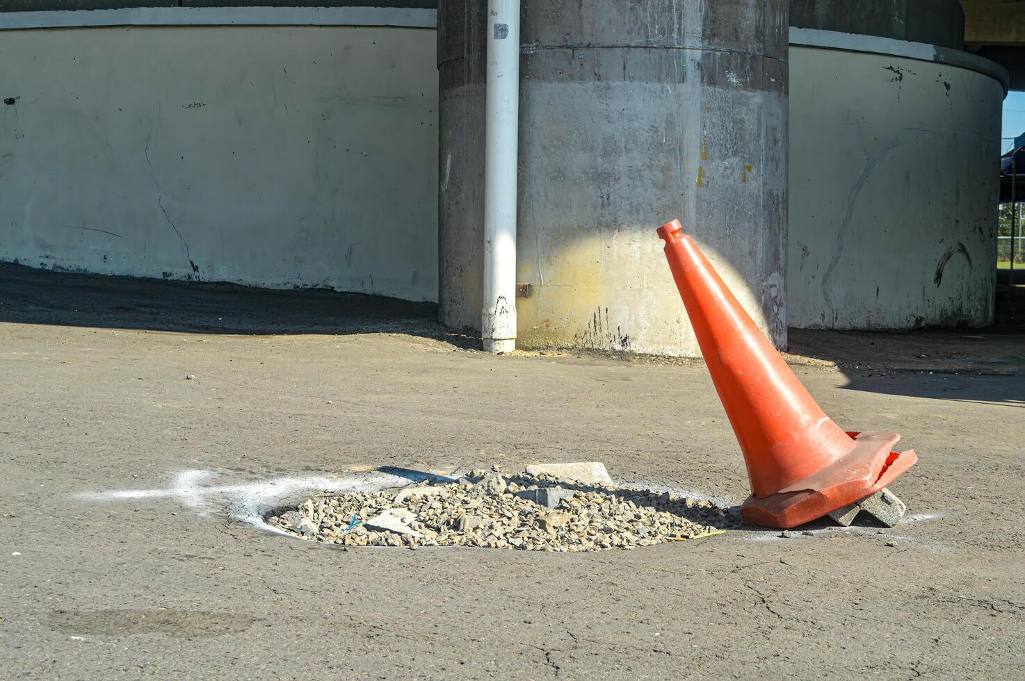 a traffic cone placed near a pothole as a sign photo