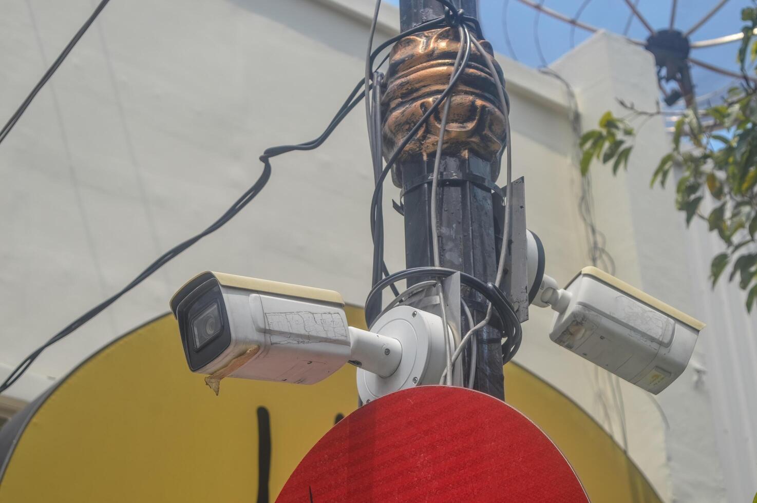 A CCTV surveillance camera attached to an electricity pole is monitoring the city photo