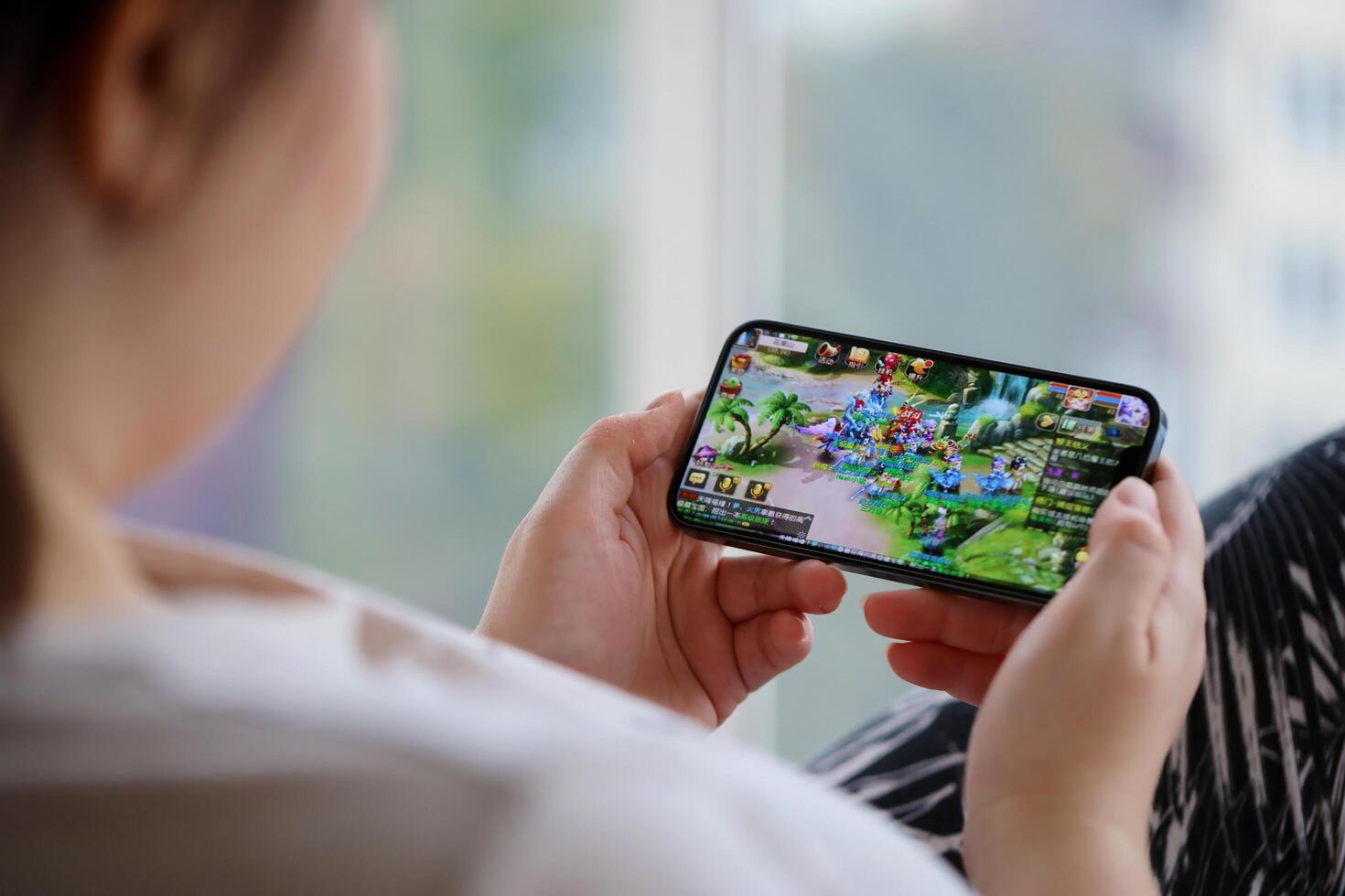 Fantasy Westward Journey mobile iOS game on iPhone 15 smartphone screen in female hands during mobile gameplay photo