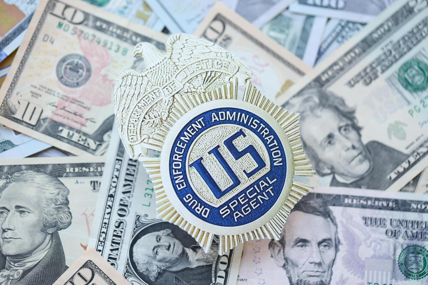 KYIV, UKRAINE - MARCH 9, 2024 US DEA Special Agent badge on many US dollar bills photo