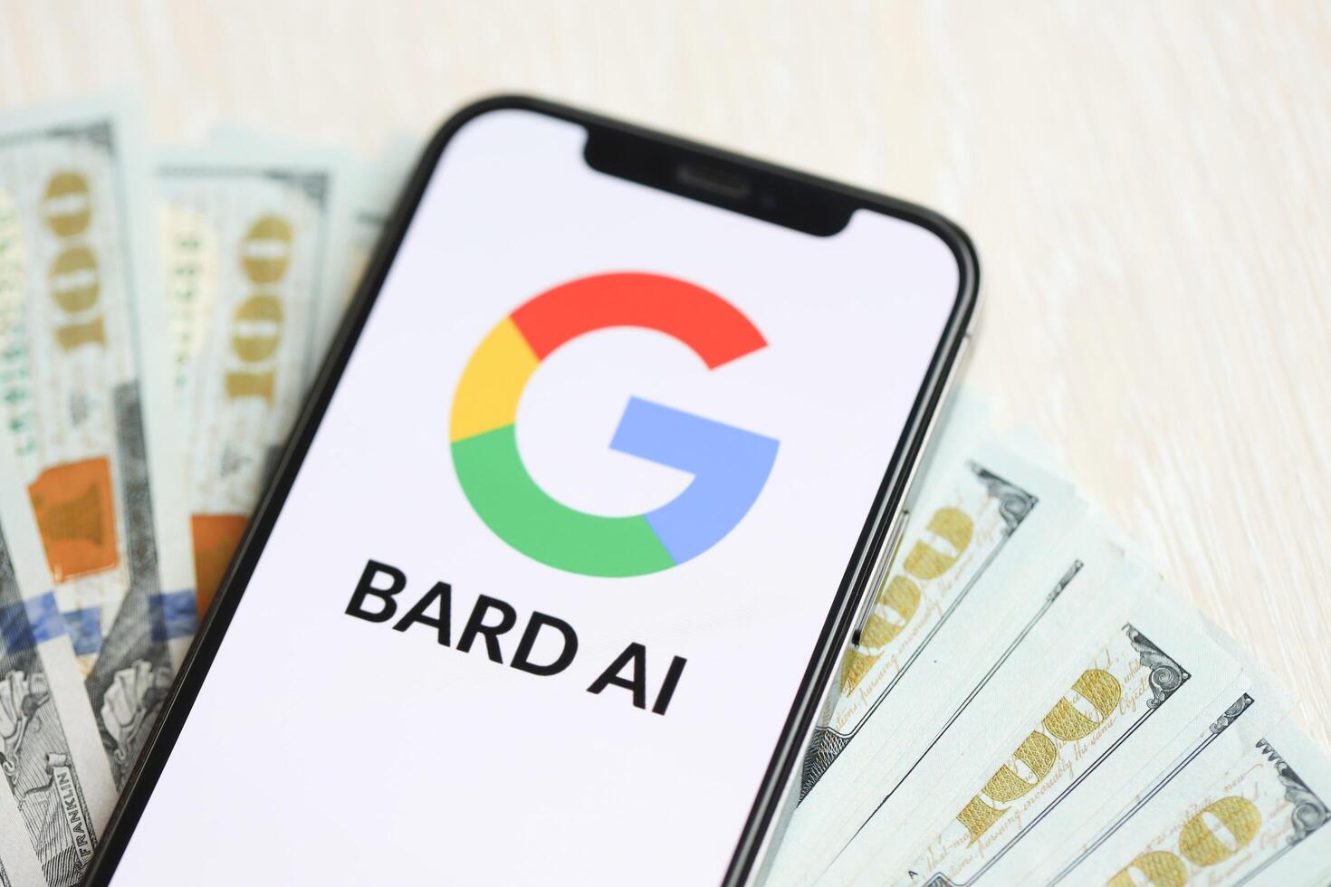 KYIV, UKRAINE - MARCH 17, 2024 Google Bard logo on iPhone display screen with many hundred dollar bills photo