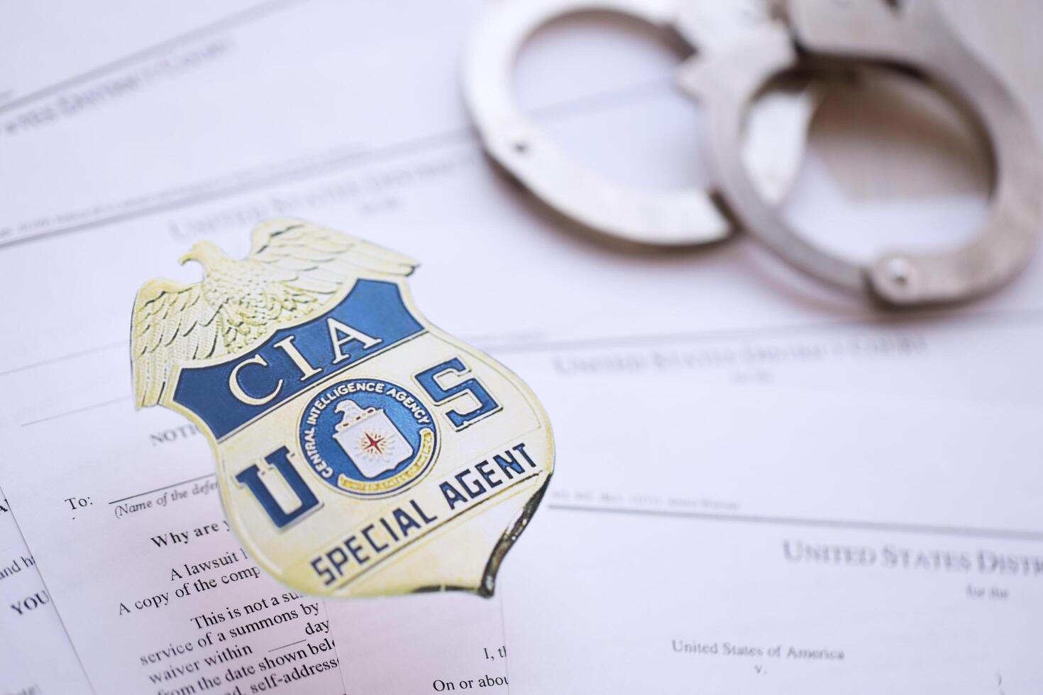 KYIV, UKRAINE - MARCH 9, 2024 US CIA Central Intelligence Agency badge with handcuffs on many US District Court warrants and complaints photo